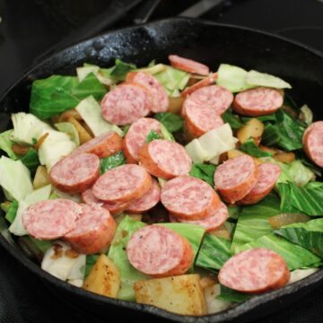 Cabbage, sausage and potatoes in cast iron skillet.