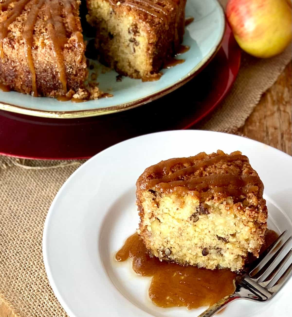 Apple cake slice with glaze on white plate.