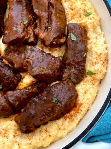 Braised ribs in a Dutch oven nestled over a bed of cheese grits.