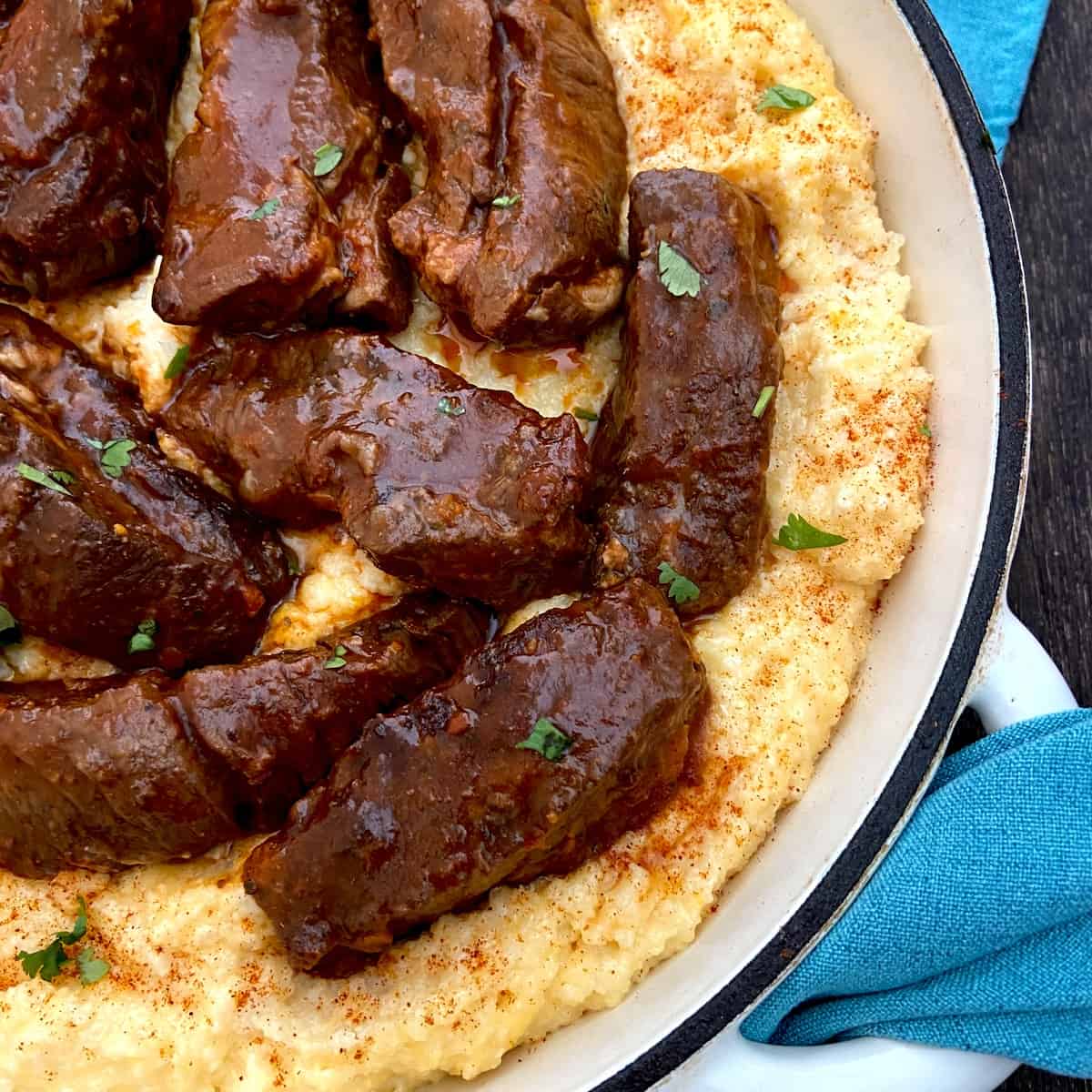 Braised ribs in a Dutch oven nestled over a bed of cheese grits.