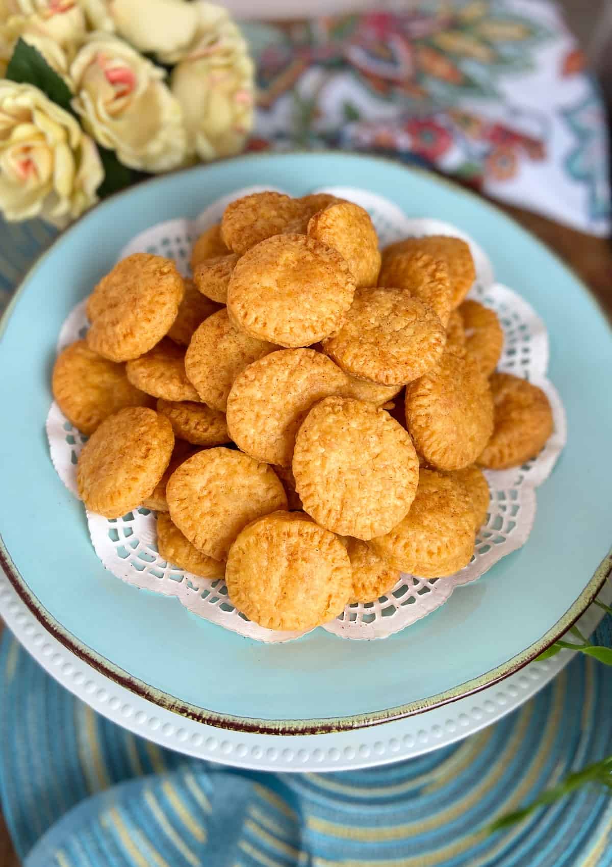 Cheddar cheese wafers on turquoise serving platter with white doiley.