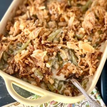 Green bean casserole in baking dish with serving spoon.