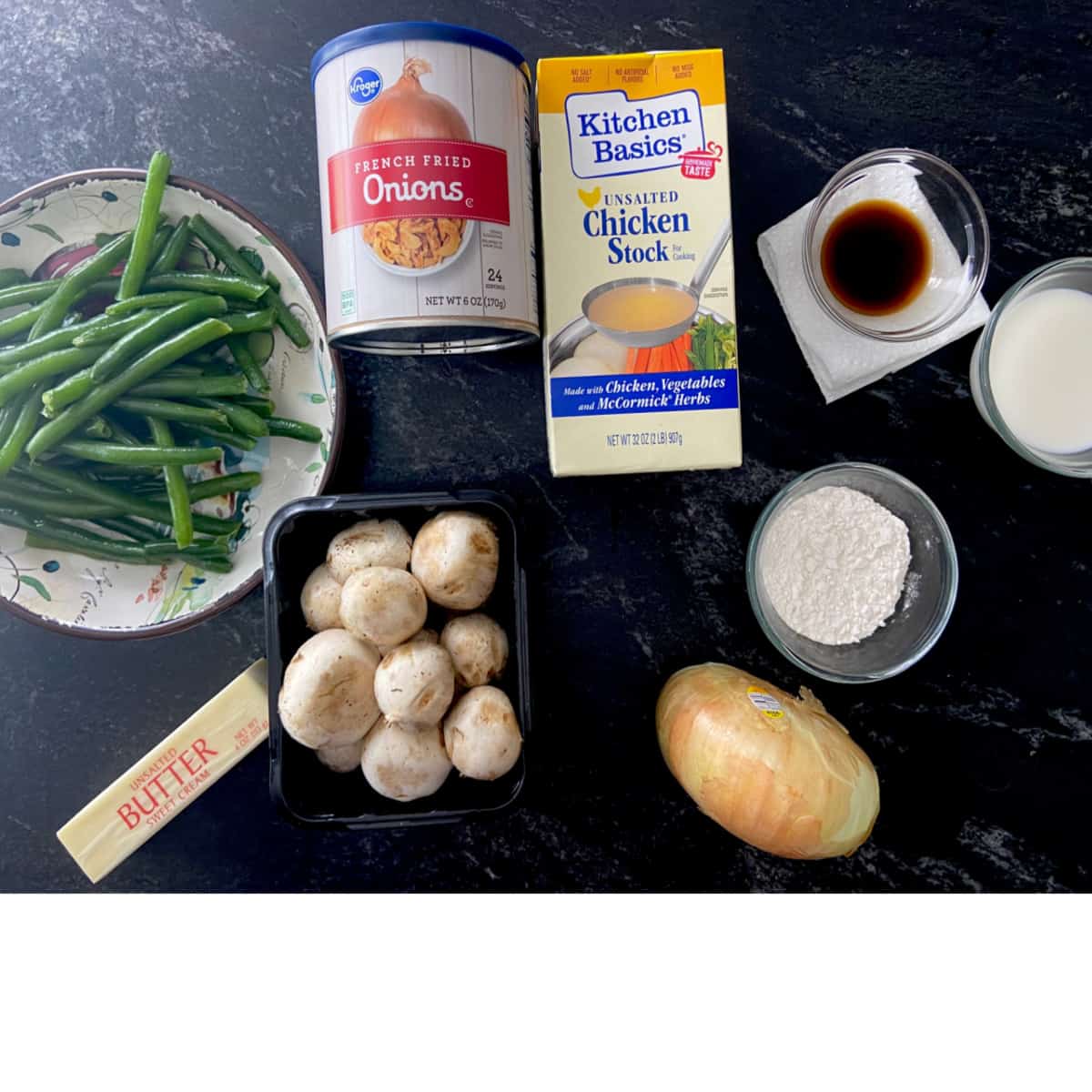 Green bean casserole ingredients on black marble countertop.