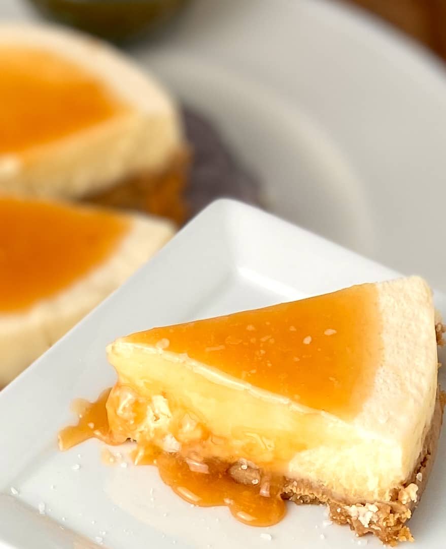 Slice of salted caramel cheesecake on white saucer.