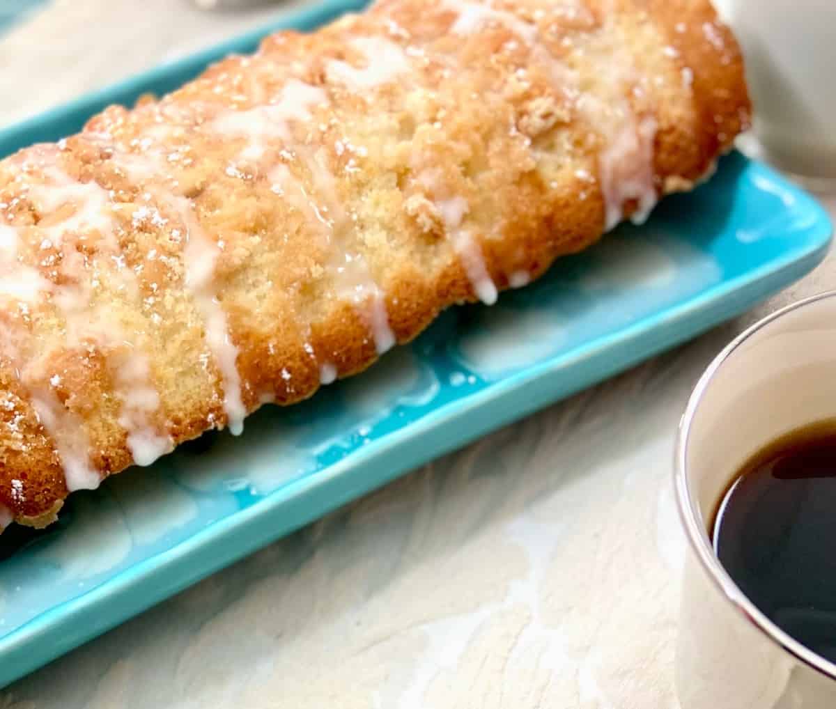 Scandinavian almond cake with glaze on turquoise serving platter.