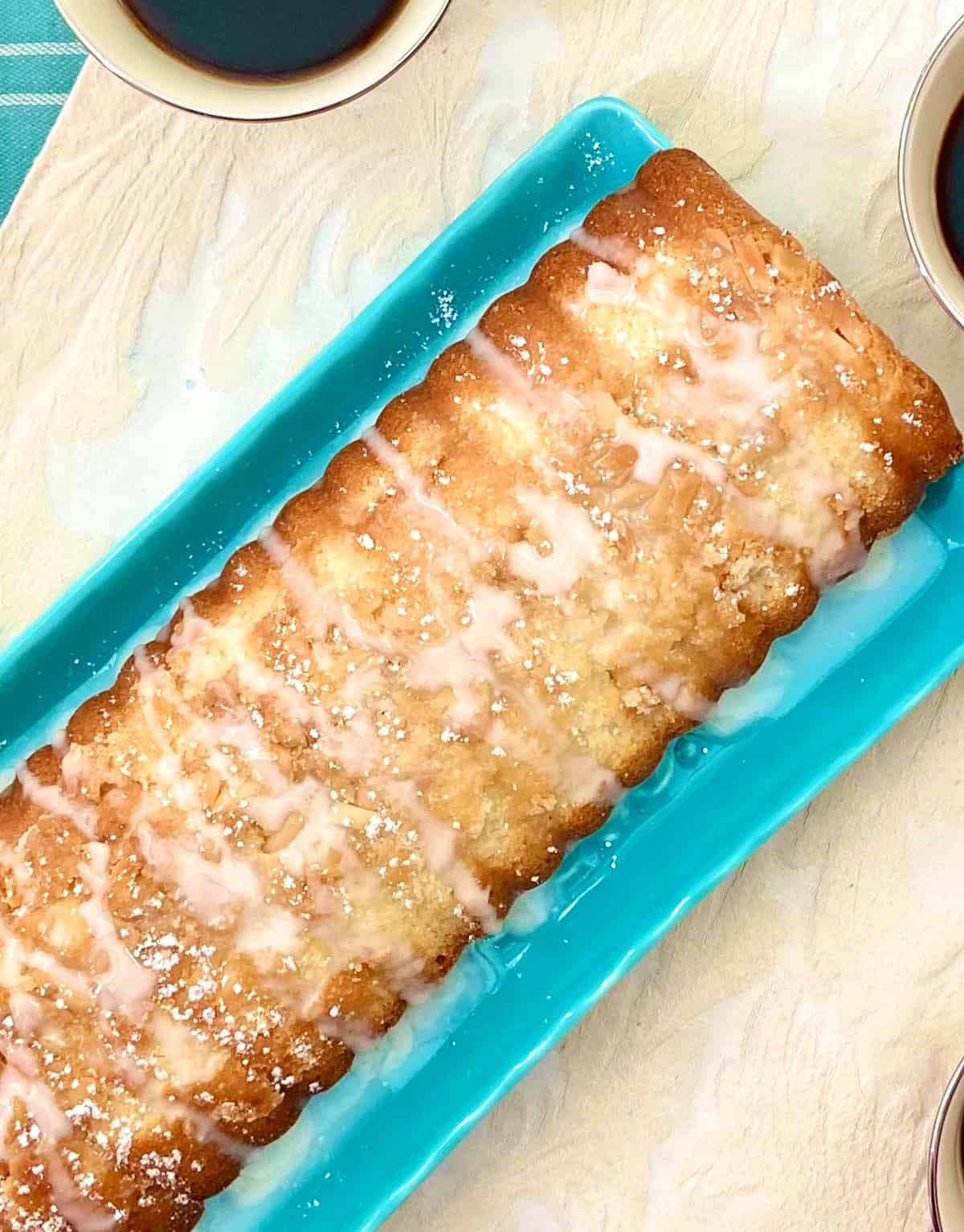 Scandinavian almond cake with glaze and powdered sugar on serving plate.