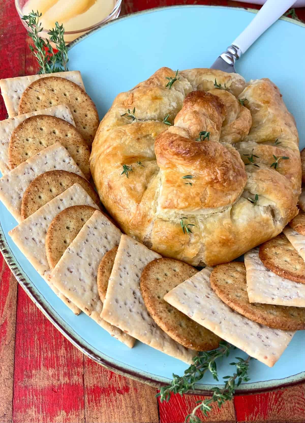 Baked brie on turquoise plate with crackers.