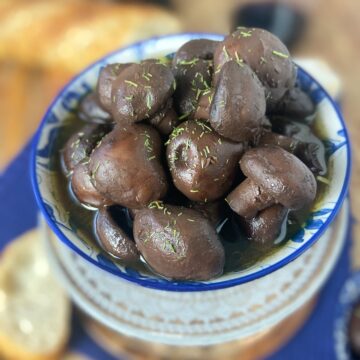 Red wine marinated mushrooms in decorative blue bowl.