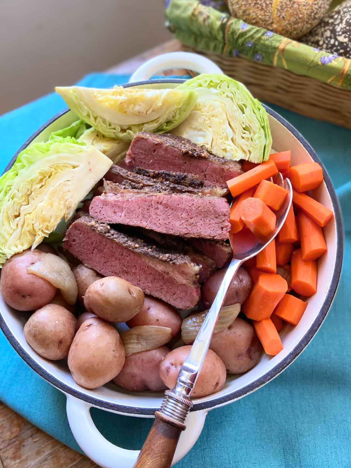 Corned beef, cabbage, carrots and potatoes in stockpot with serving spoon.