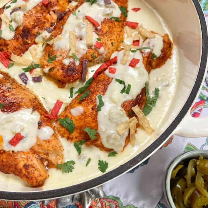 Mexican chicken with sour cream sauce in shallow baking dish.