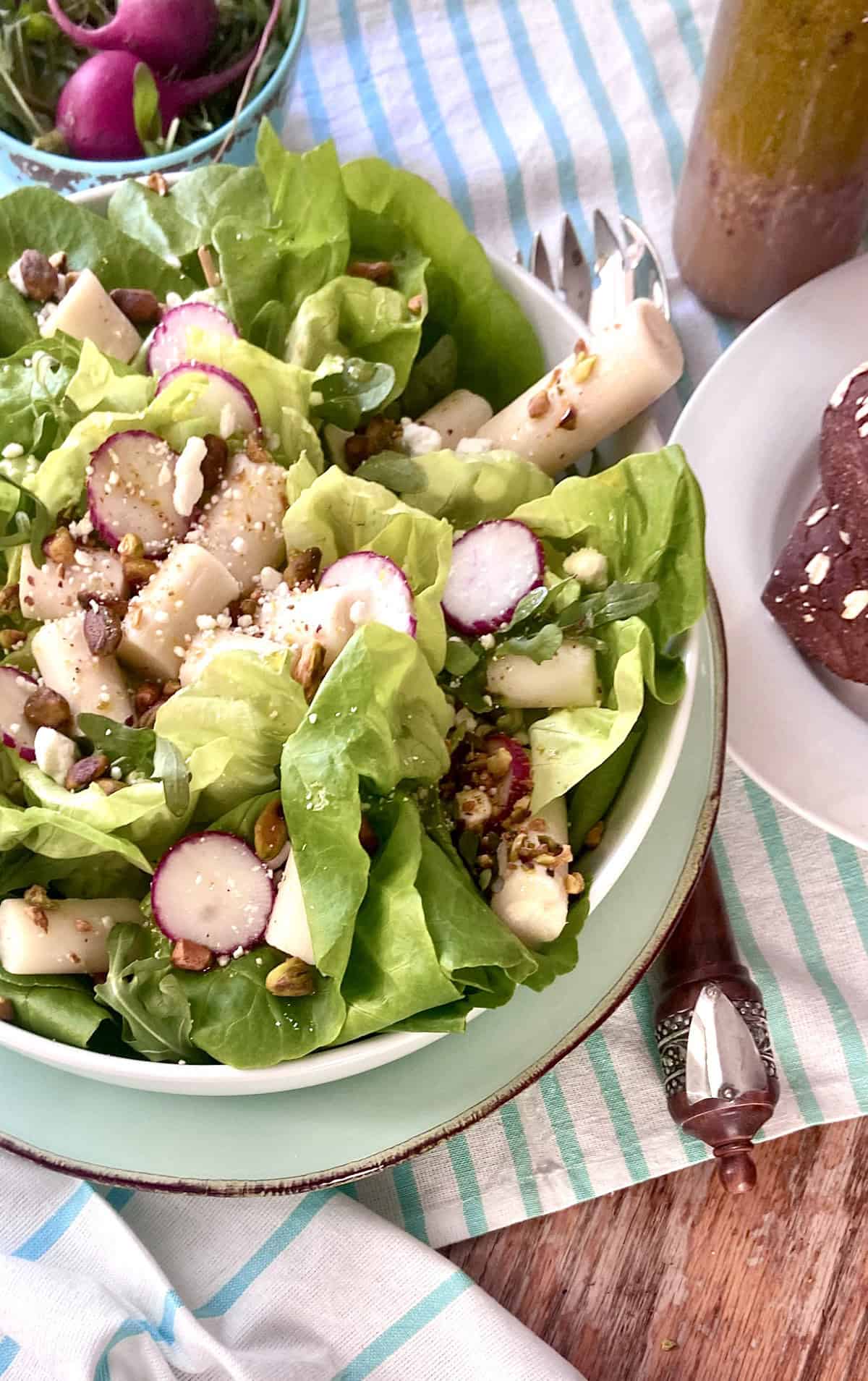 Hearts of palm salad with butter lettuce in white bowl.