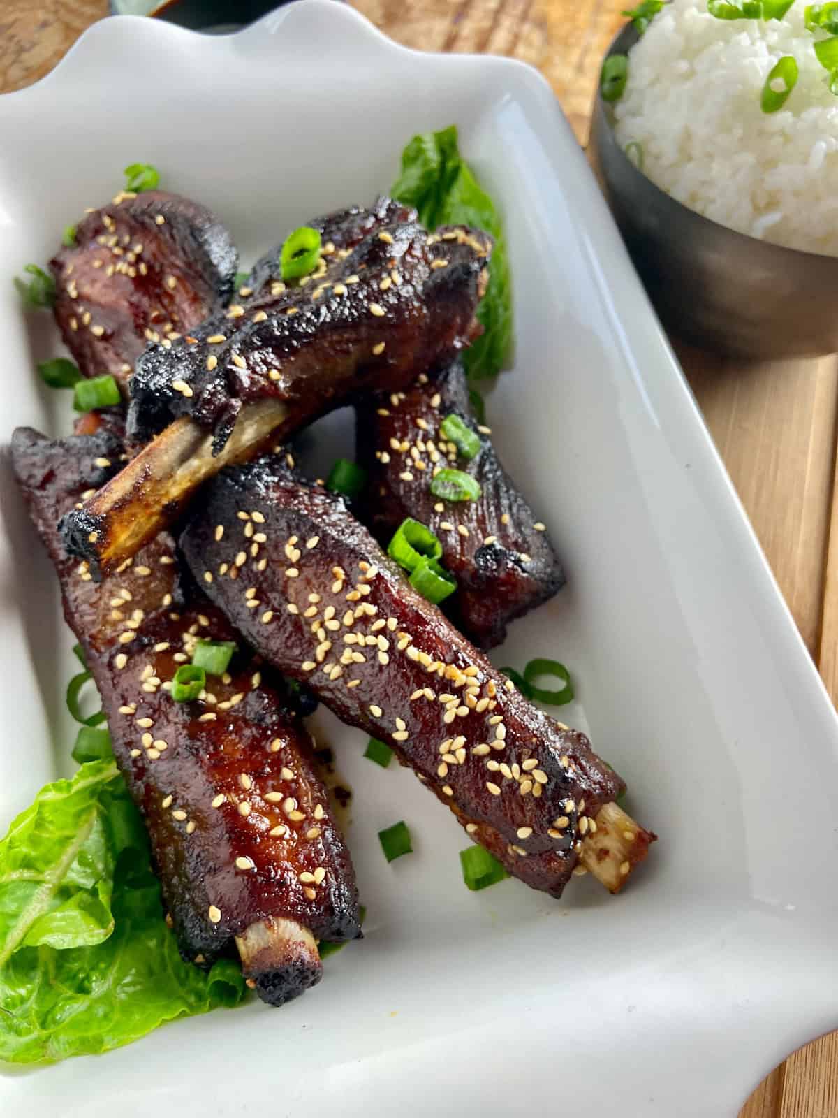 Asian sticky ribs in a white shallow serving platter.