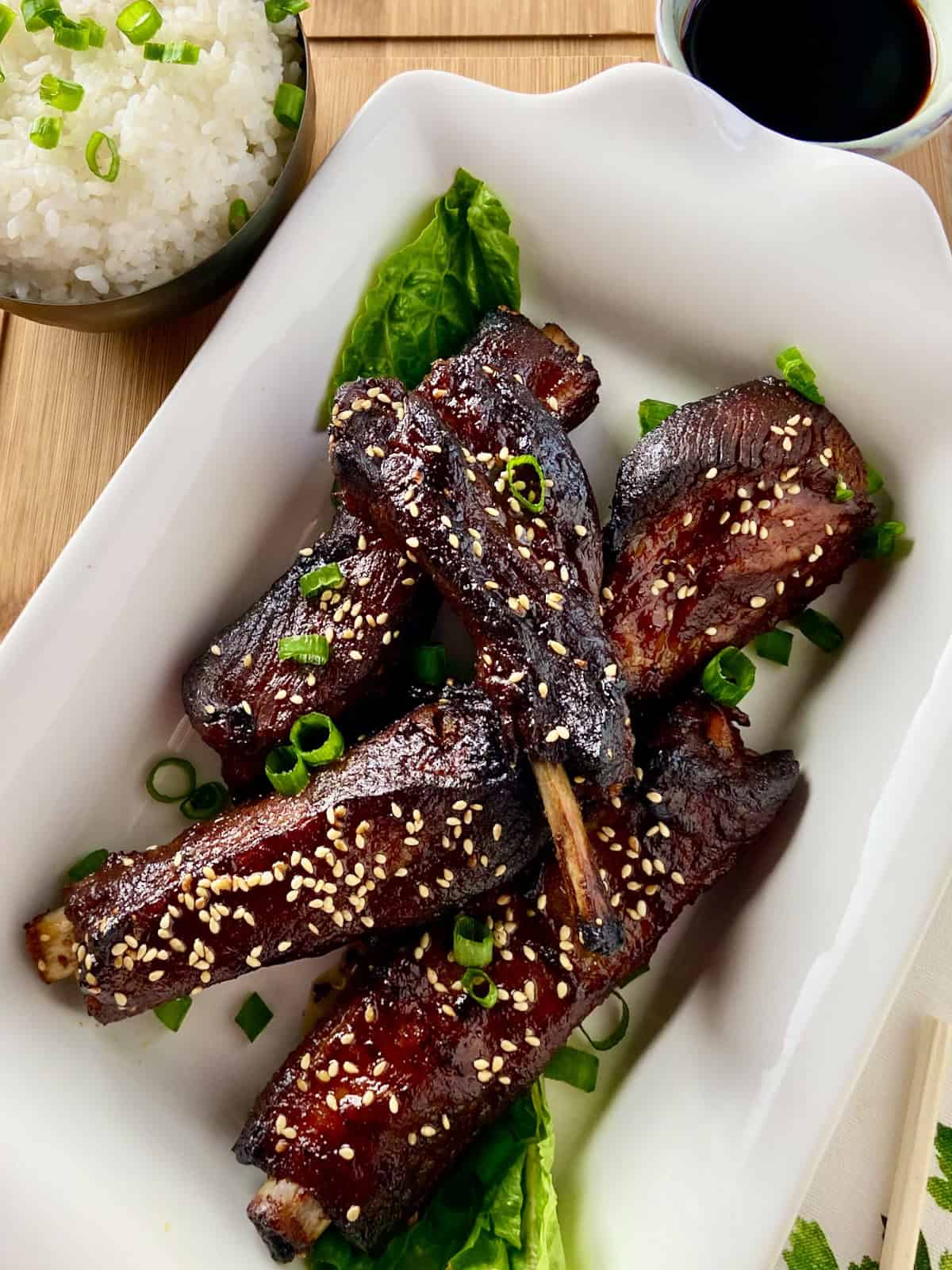 Asian sticky pork ribs in white serving platter.