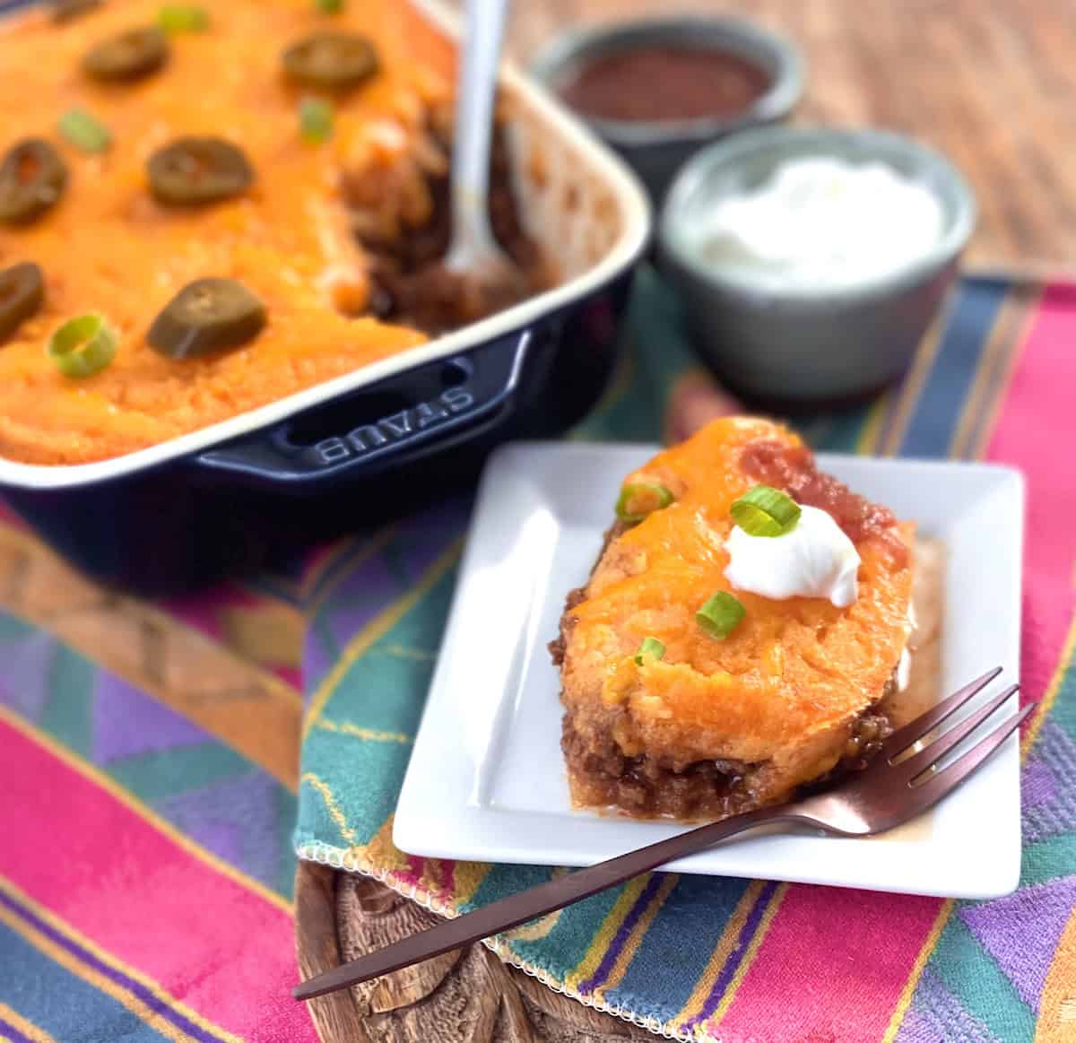 A scoop of tamale pie casserole on white dish with copper fork.
