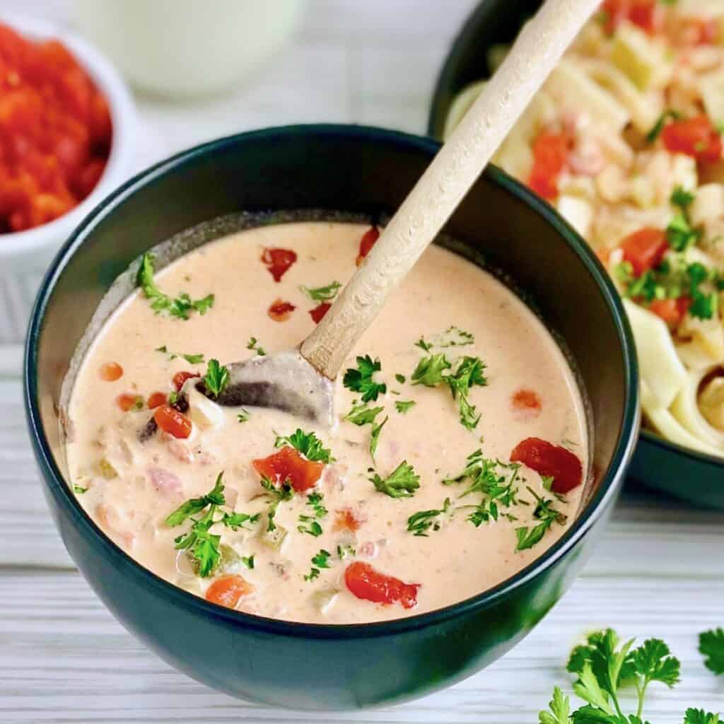 Creole cream sauce in black bowl with wooden serving spoon.