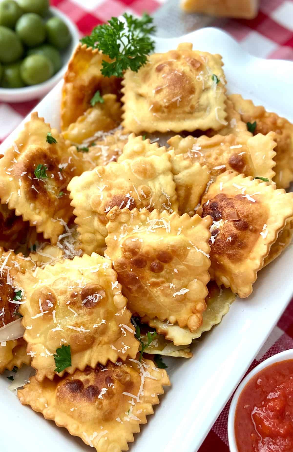 Fried ravioli on white serving tray.