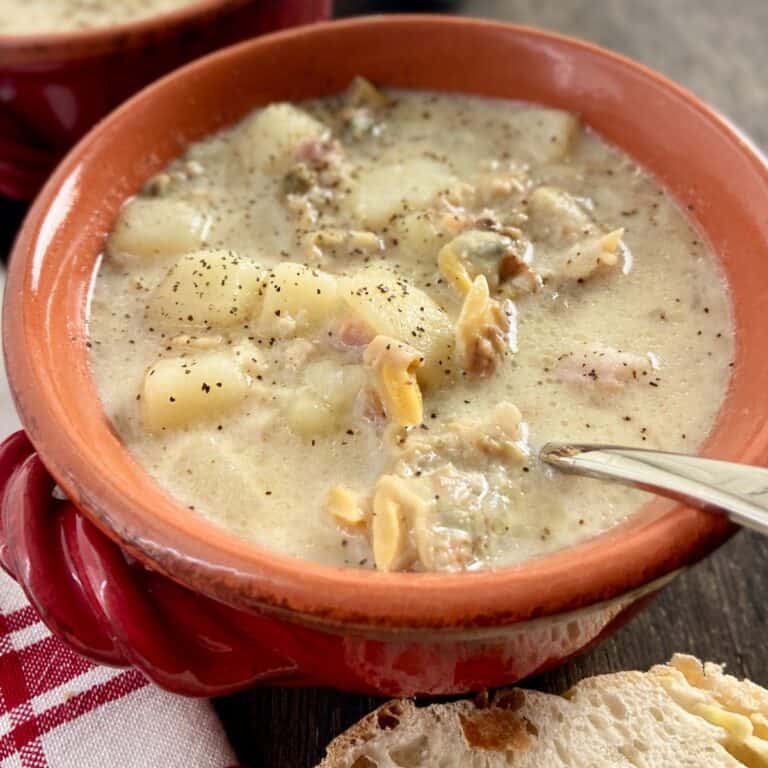 New England Clam Chowder in red bowl with spoon.