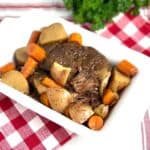 Pot roast and vegetables in white baking dish.