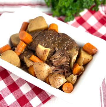 Pot roast and vegetables in white baking dish.