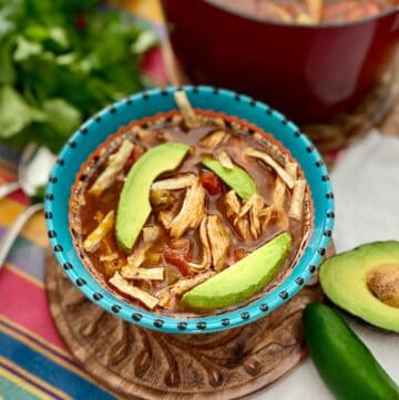 Tortilla soup in decorative bowl garnished with avocado slices.