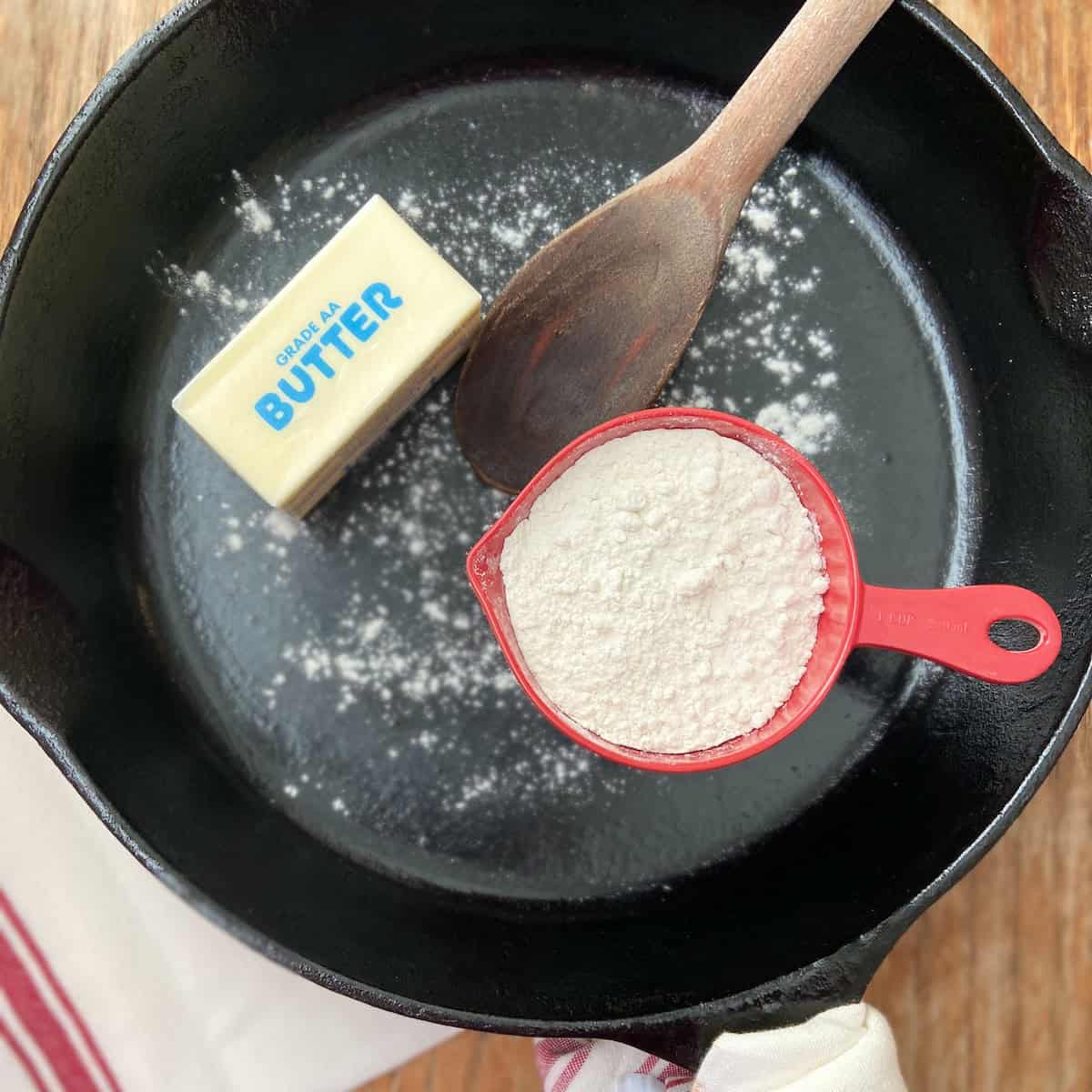 Cup of flour and a stick of butter in a cast iron skillet.