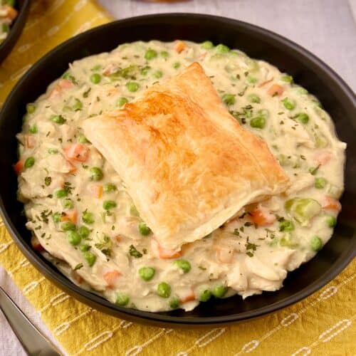 Chicken pot pie soup with puff pastry on top.