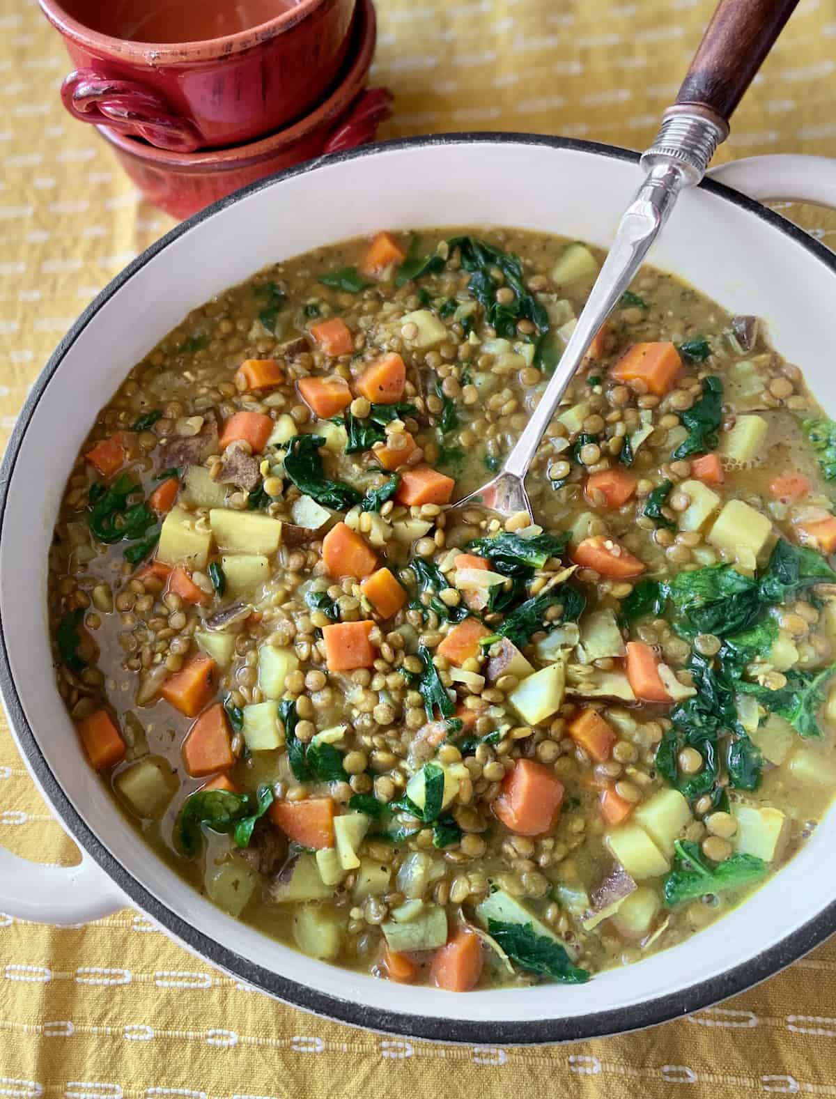 Lentil and Potato stew in Dutch oven with serving spoon.