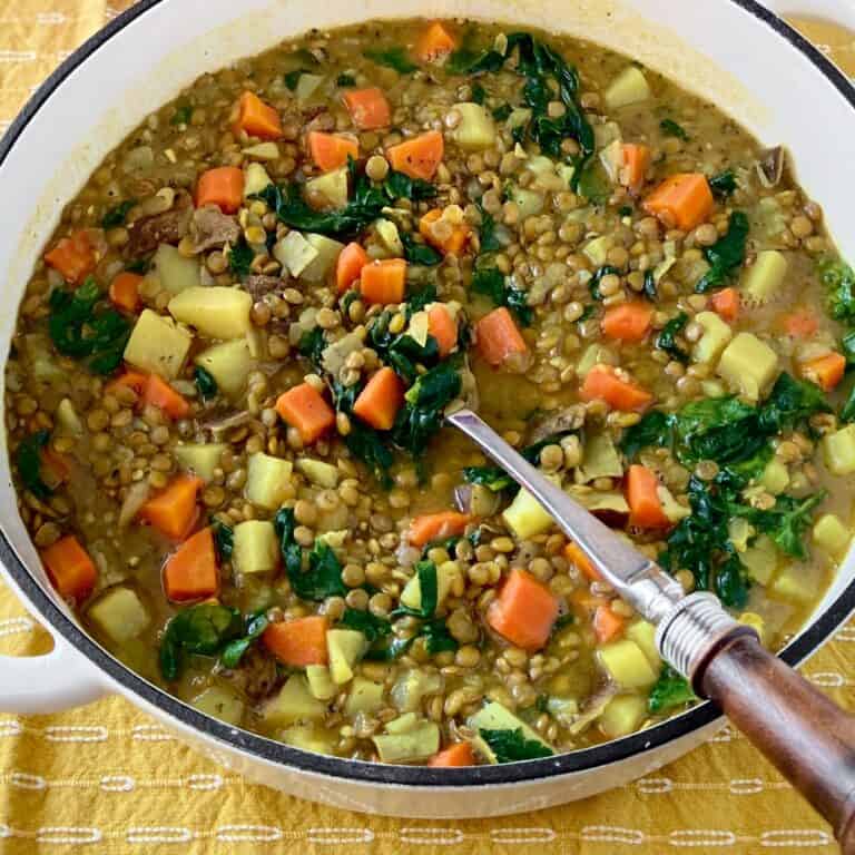 Lentil and potato stew in Dutch oven with serving spoon.