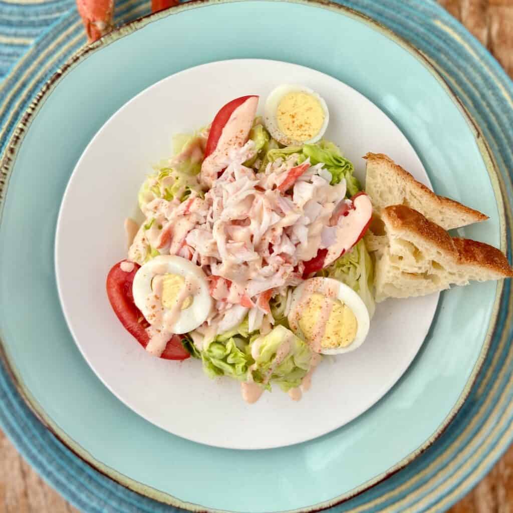 Crab Louie dressing drizzled over salad on white plate.