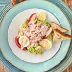Crab Louie dressing drizzled over salad on white plate.