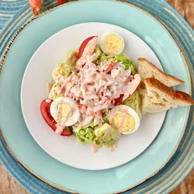 Crab Louie dressing drizzled over salad on white plate.