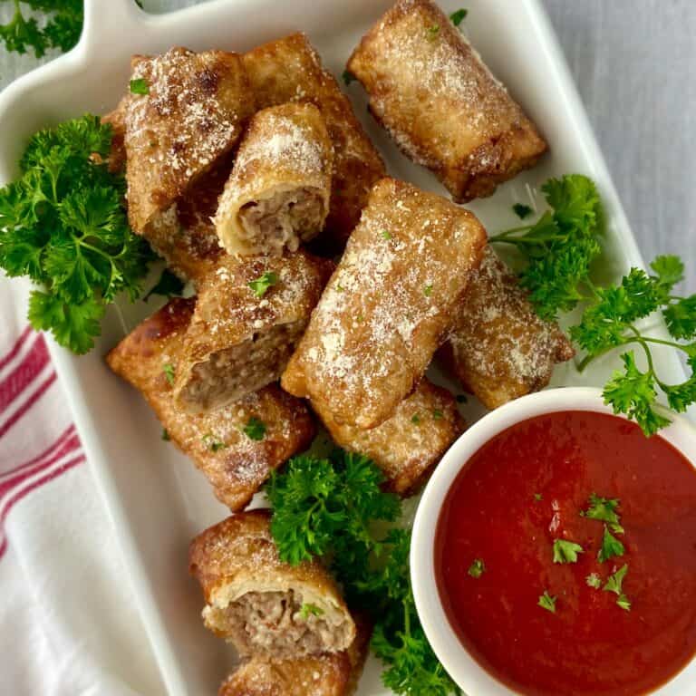 Italian egg rolls on white serving platter with a side of marinara.