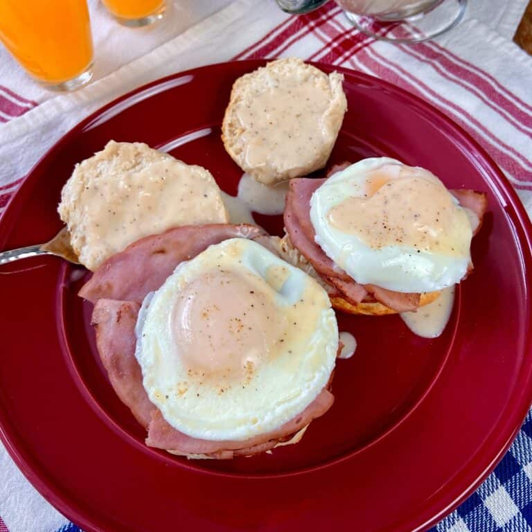 Country style eggs benedict on a biscuit with ham and cream gravy.