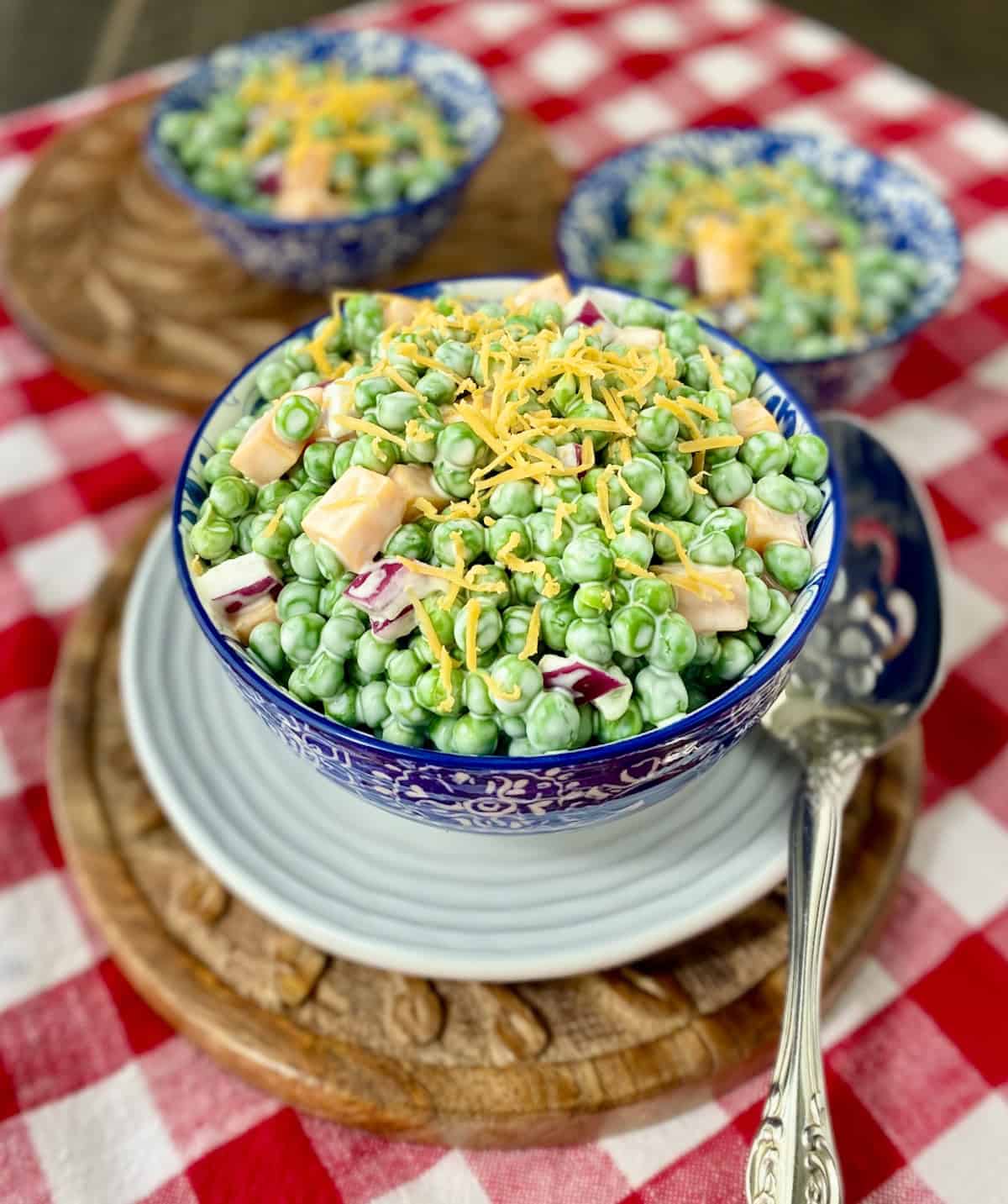 English Pea Salad in a blue and white decorative bowl with a slotted spoon.
