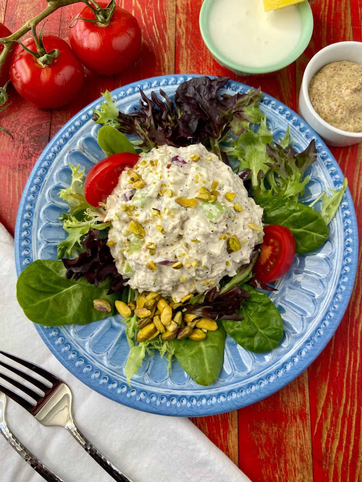Pistachio Chicken Salad on a bed of greens on blue plate.