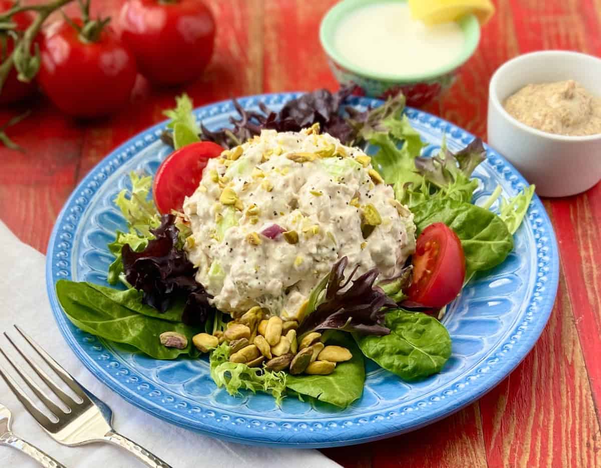 Pistachio Chicken Salad on a bed of spring greens on a blue plate.