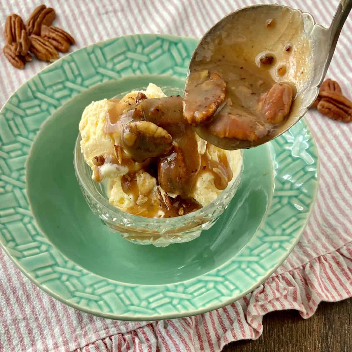 Pecan praline sauce in spoon over vanilla ice cream
