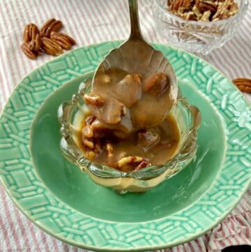 Pecan praline sauce in silver serving spoon.