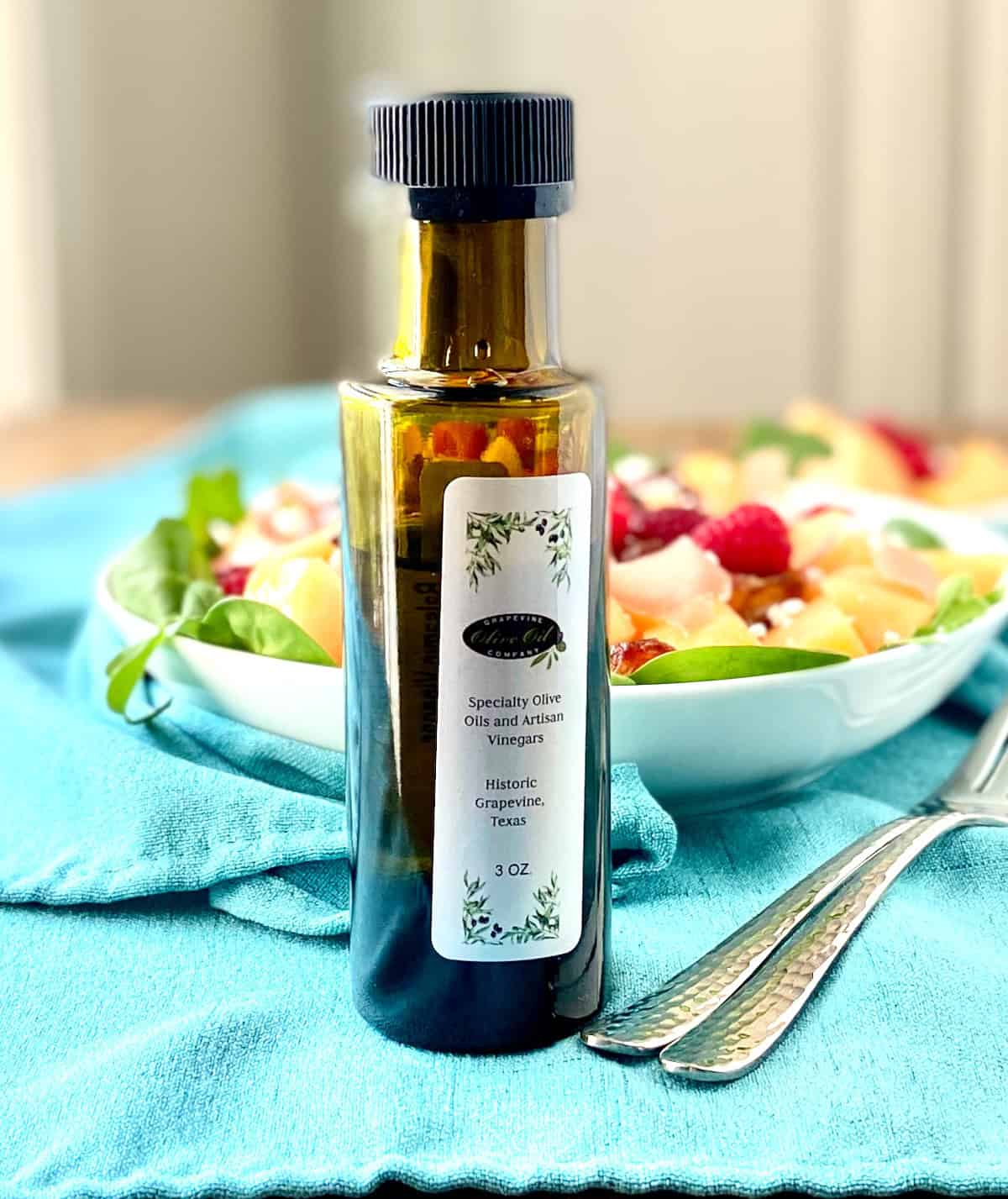 Bottle of specialty balsamic vinegar in front of fruit salad.