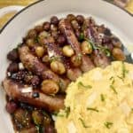 Italian sausage in skillet with grapes and balsamic vinegar.