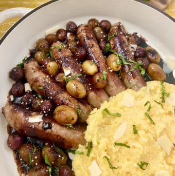 Italian sausage in skillet with grapes and balsamic vinegar.