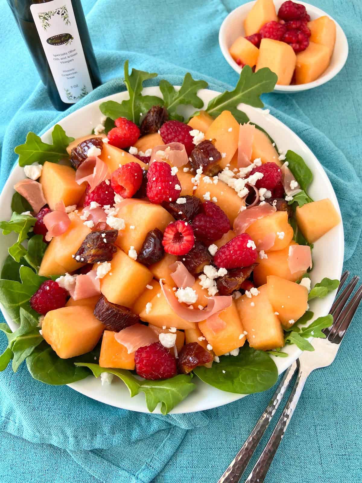Marinated fruit salad on arugula in white bowl.