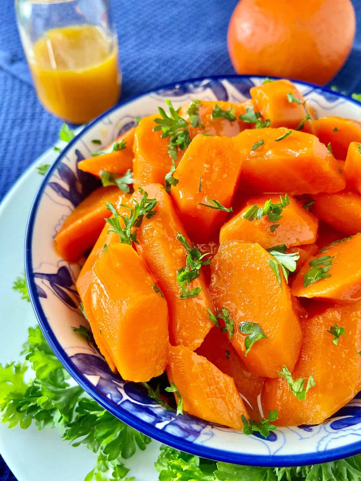 Close up image of orange glazed carrots garnished with chopped parsley.