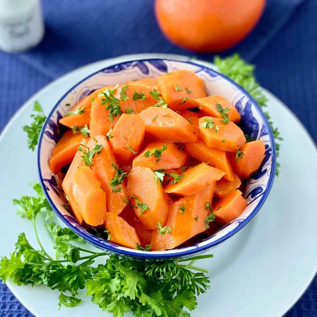 Orange Honey Glazed carrots in decorative blue bowl.
