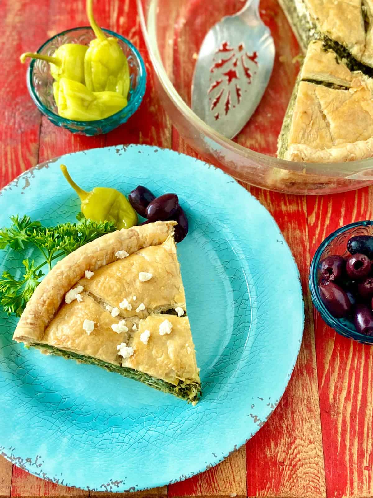 Slice of spinach pie on turquoise plate.
