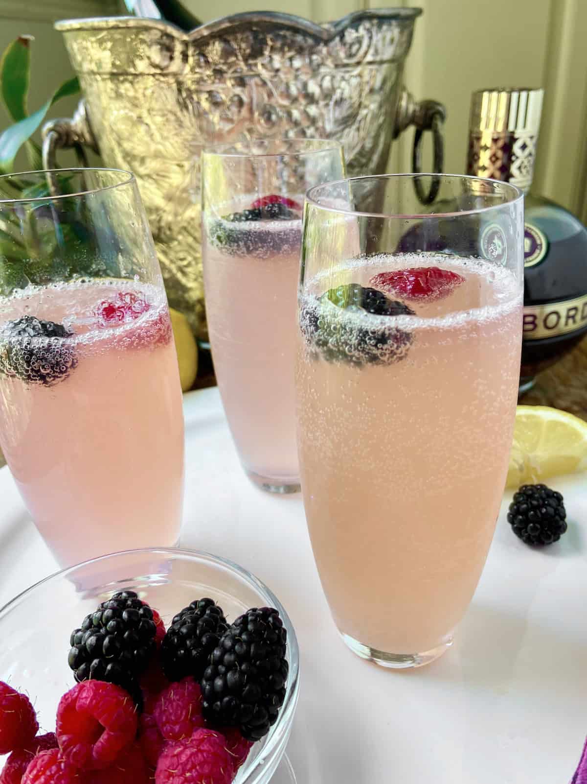 Stemless champagne flute with chambord champagne garnished with a raspberry and blackberry.
