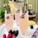 Chambord champagne cocktail in stemless champagne flute on white serving platter.