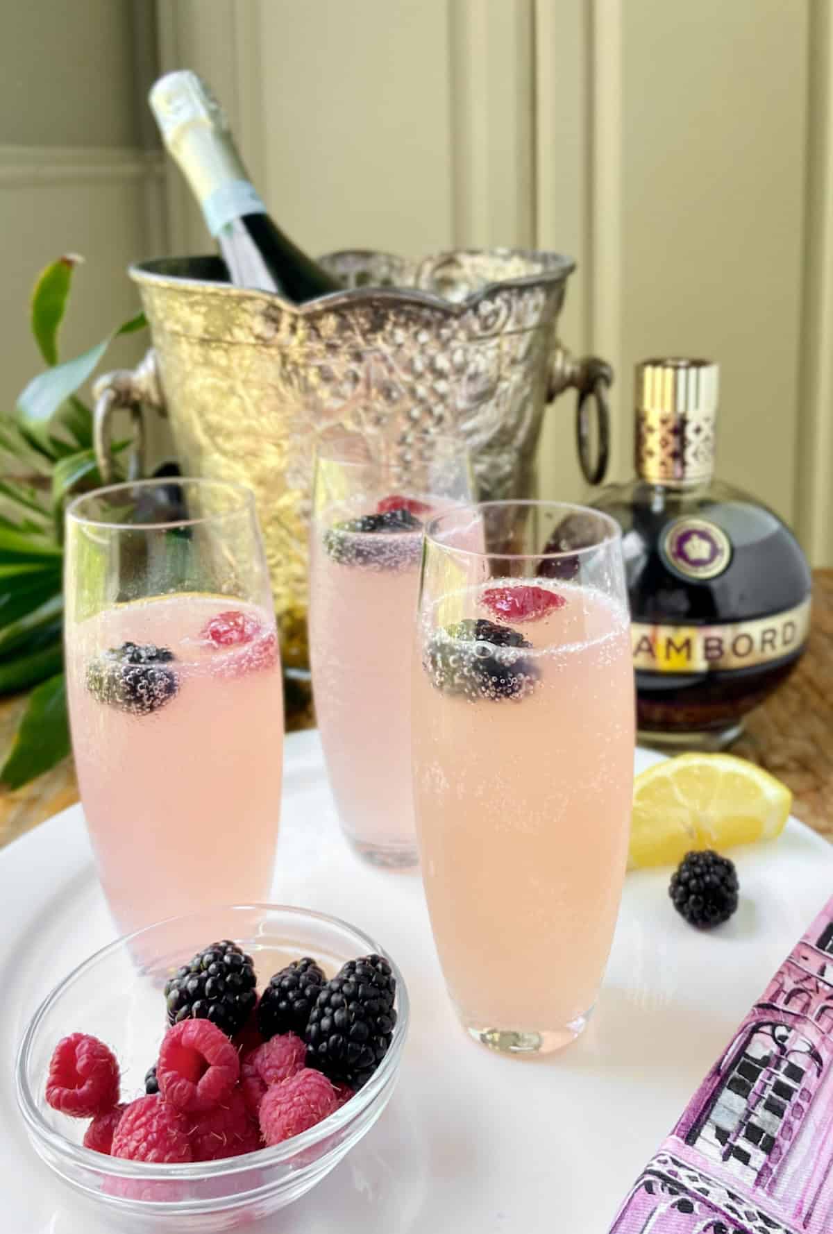 Chambord champagne in stemless champagne flute on white serving platter.