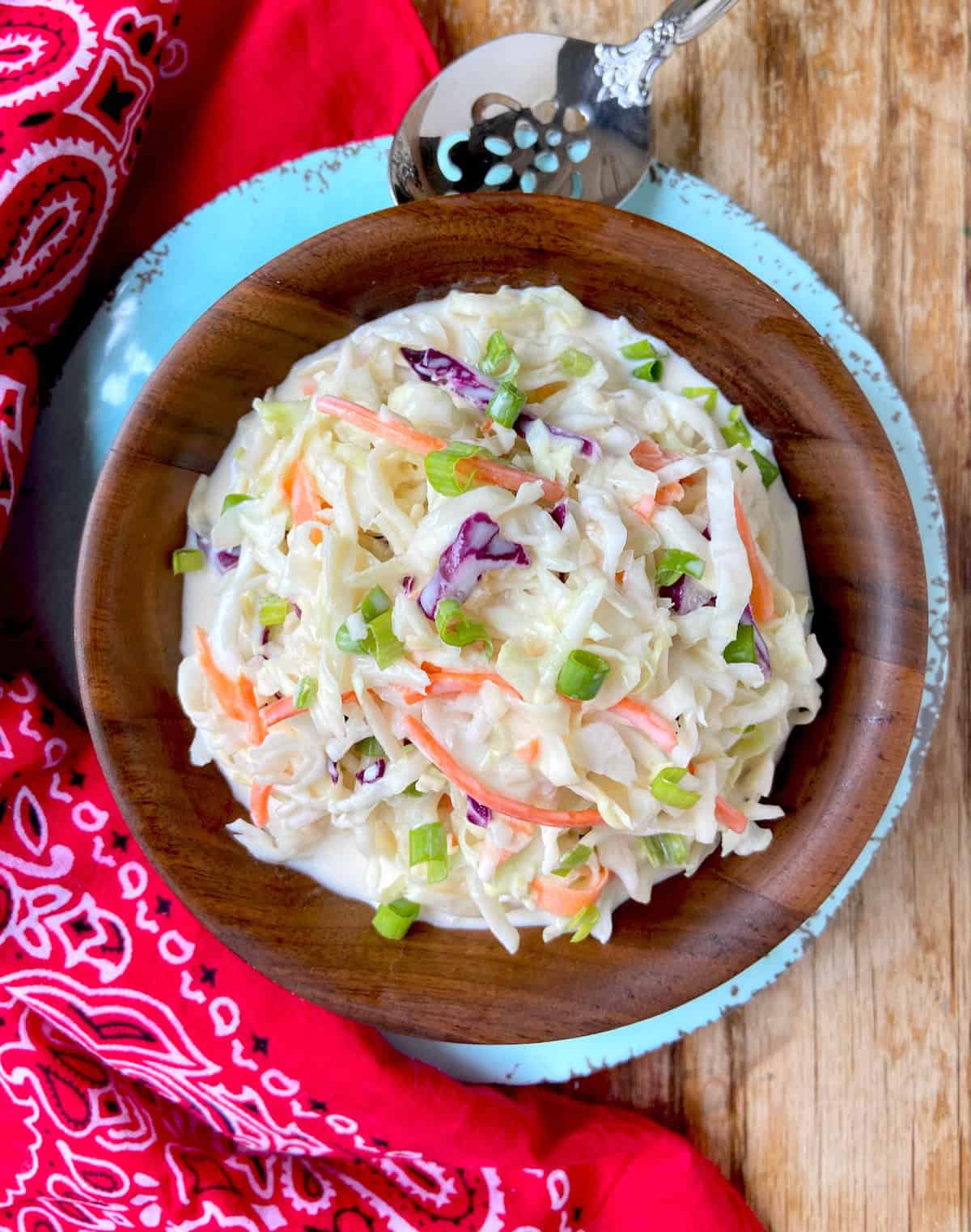 Close up of creamy coleslaw in wooden serving bowl.