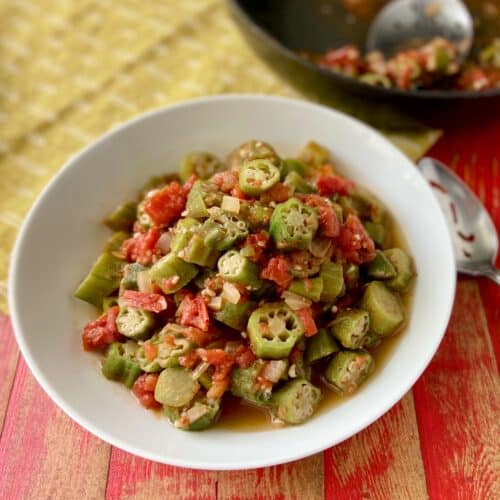 Okra and tomatoes in white serving bowl.